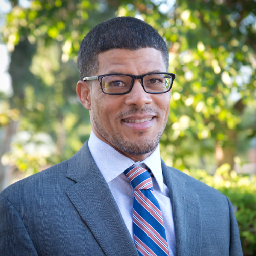Portrait of Afro-American Man Wearing a Suit with a Tie and Glasses with a Natural Background. Ayo